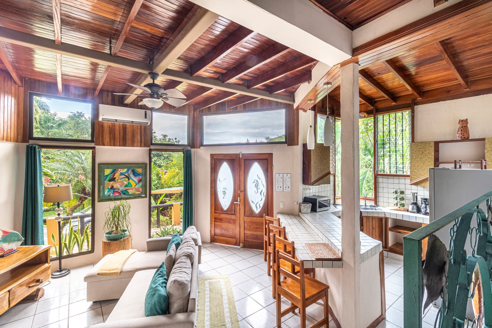 Sala abierta con cielo raso de madera y puertas al jardín