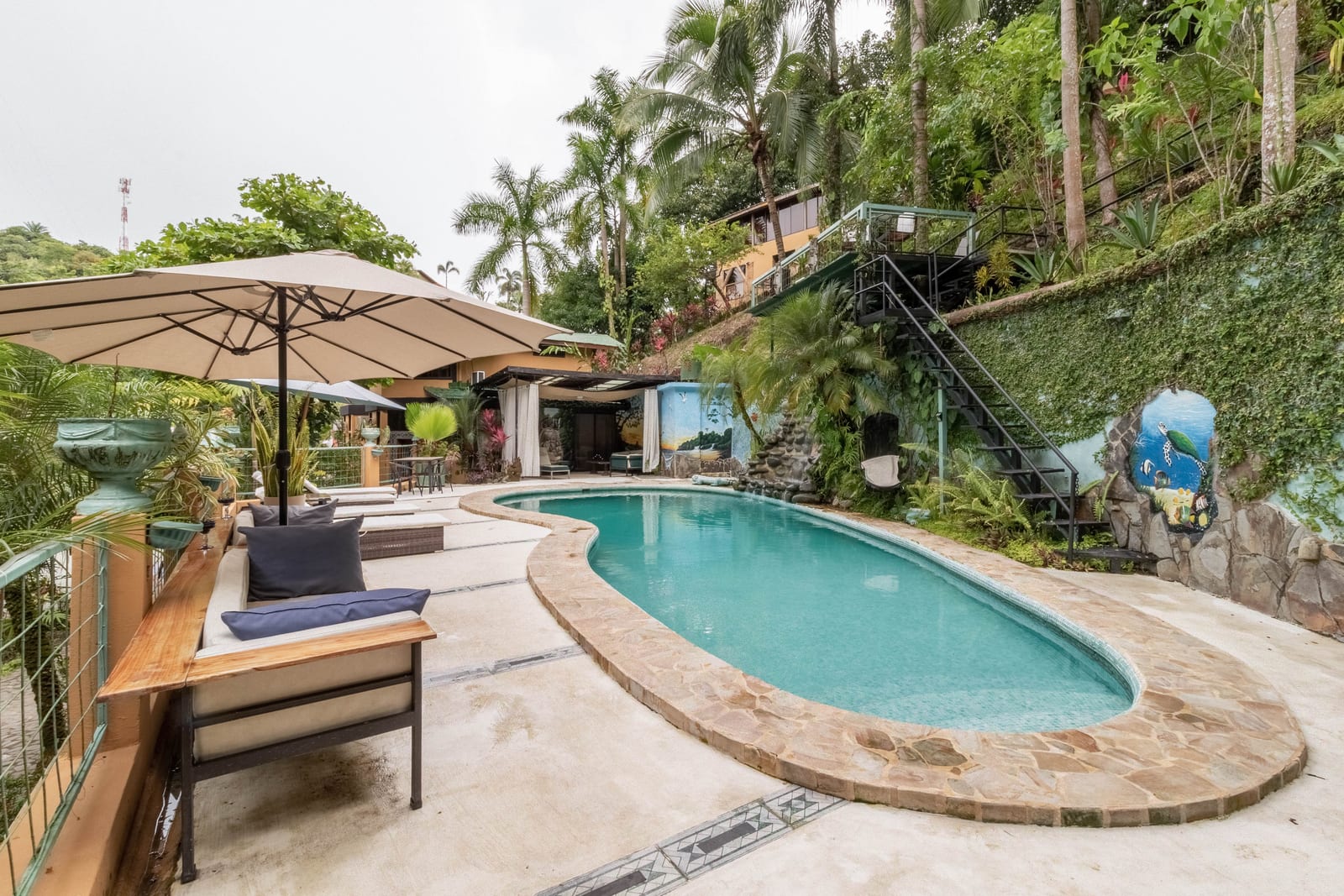 The pool terrace on the hillside, seen through palms