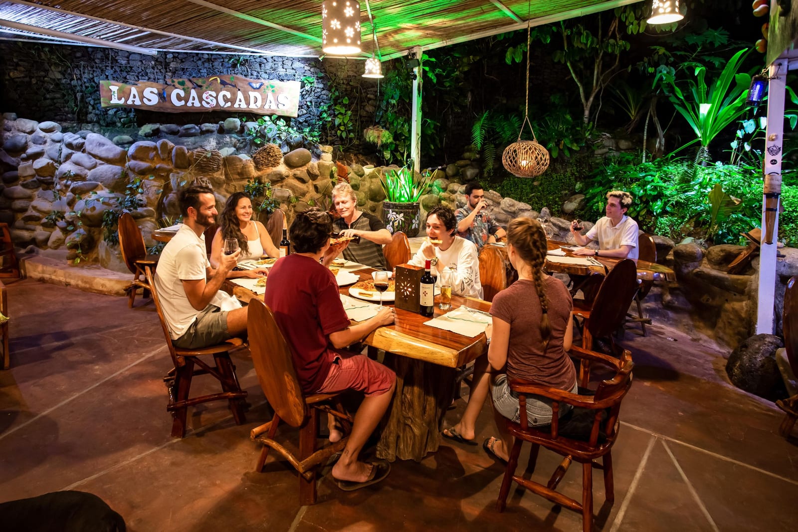 Guests at long wooden tables under the Las Cascadas sign