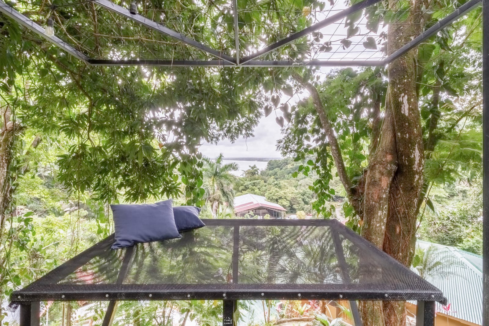 A hammock on a terrace looking out over the trees to the ocean