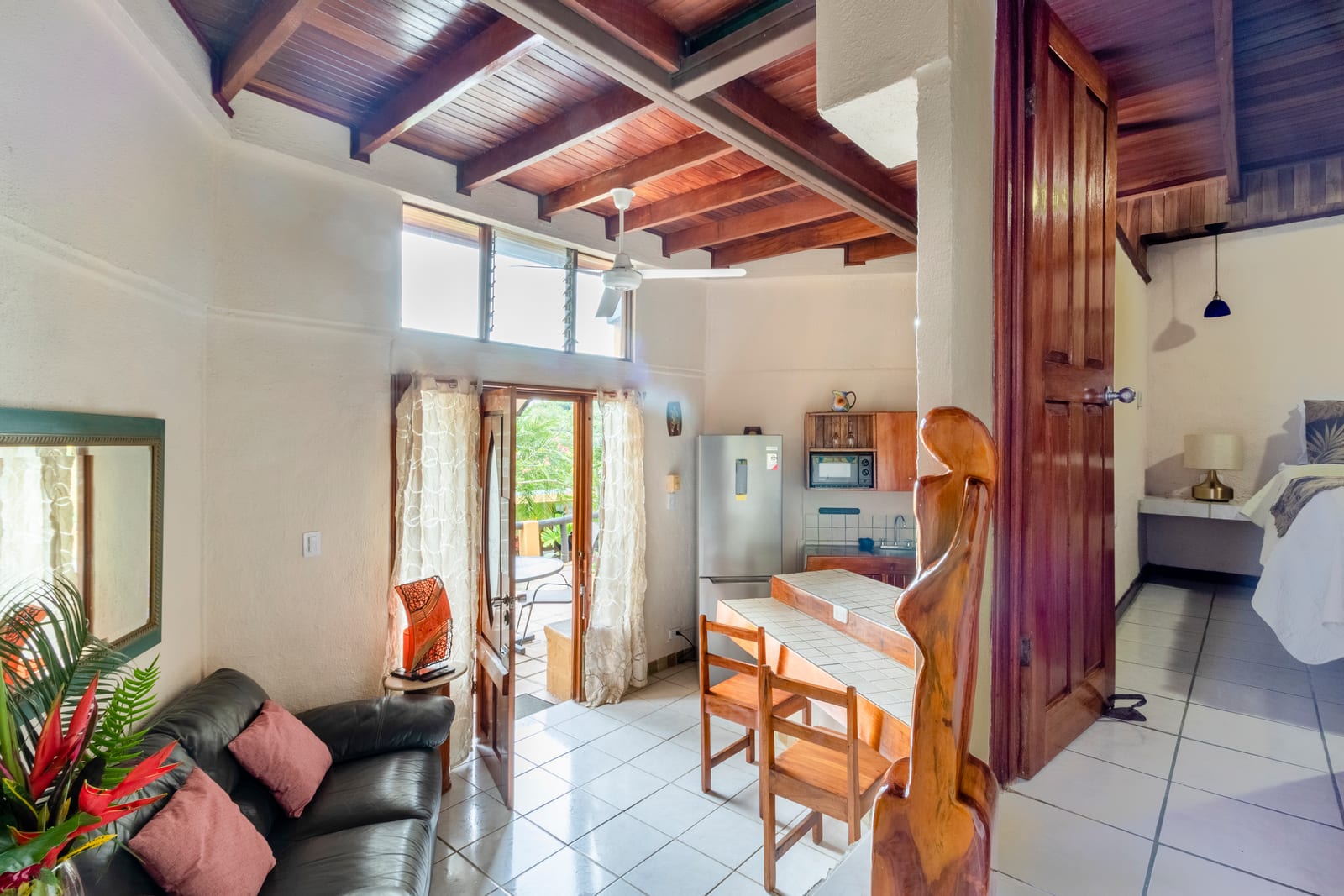 Bougainvillea Suite main level with sofa, dining table, and kitchenette under wood beams